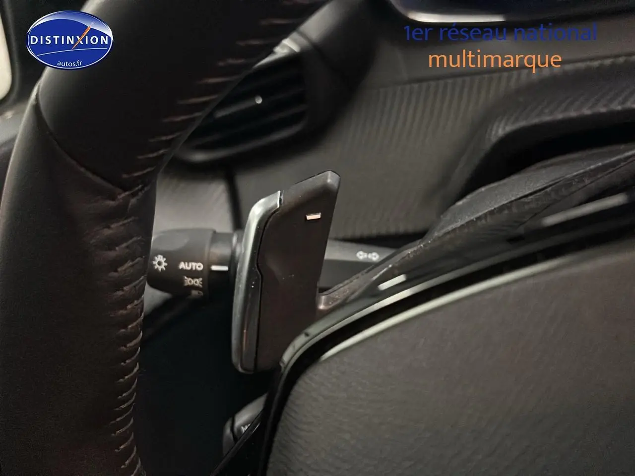 Gros plan sur la palette de changement de vitesse au volant d'une Peugeot 208 gris Artense, intérieur noir.