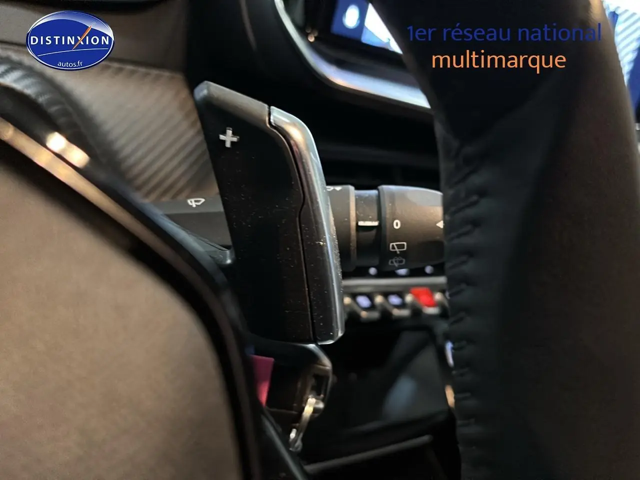 Gros plan sur la palette de changement de vitesse + du volant d’une Peugeot 208 1.2 hybrid 110 allure gris artense.