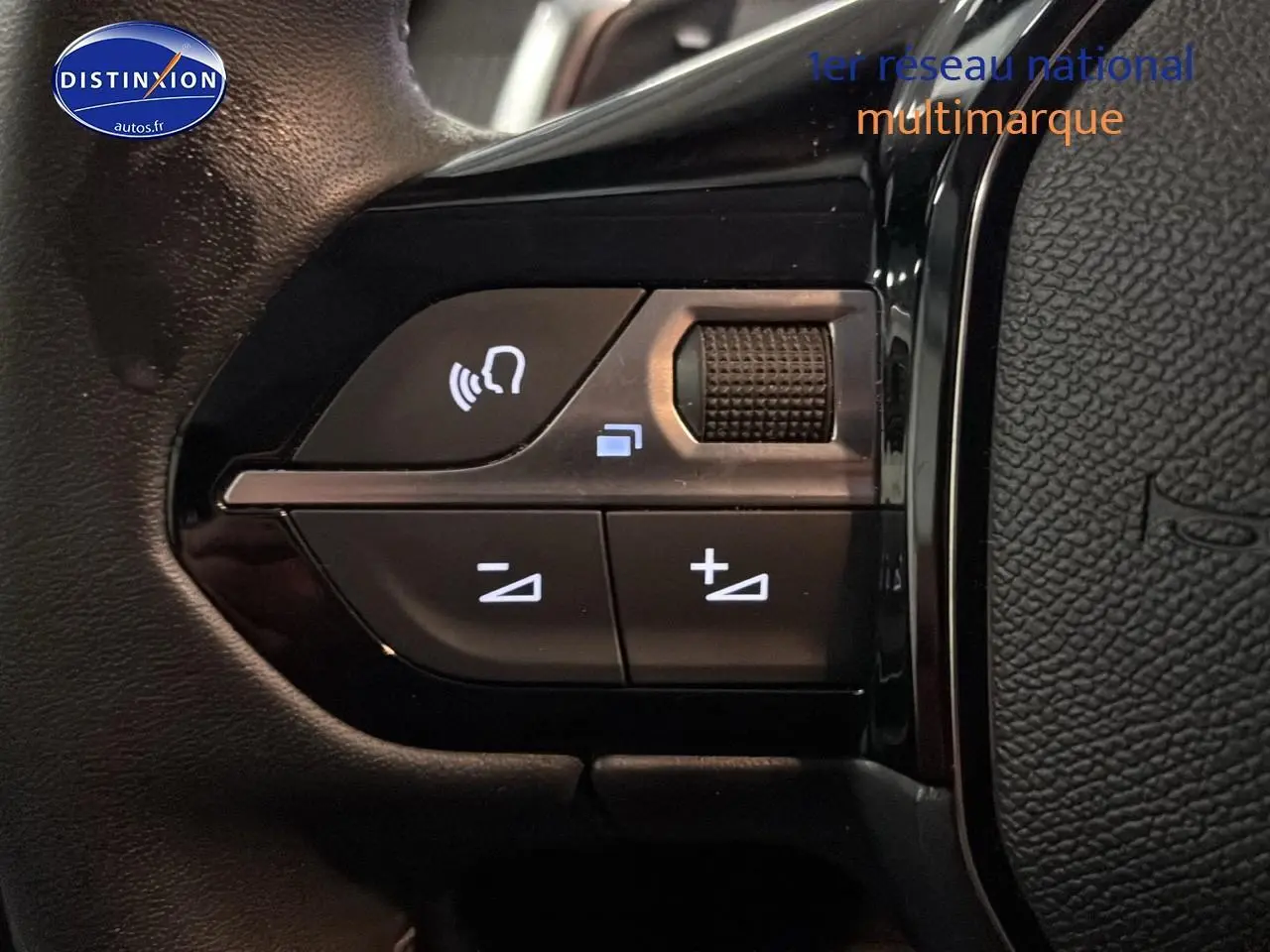 Gros plan sur les commandes audio au volant de la Peugeot 208 gris artense, version 2025 hybride.