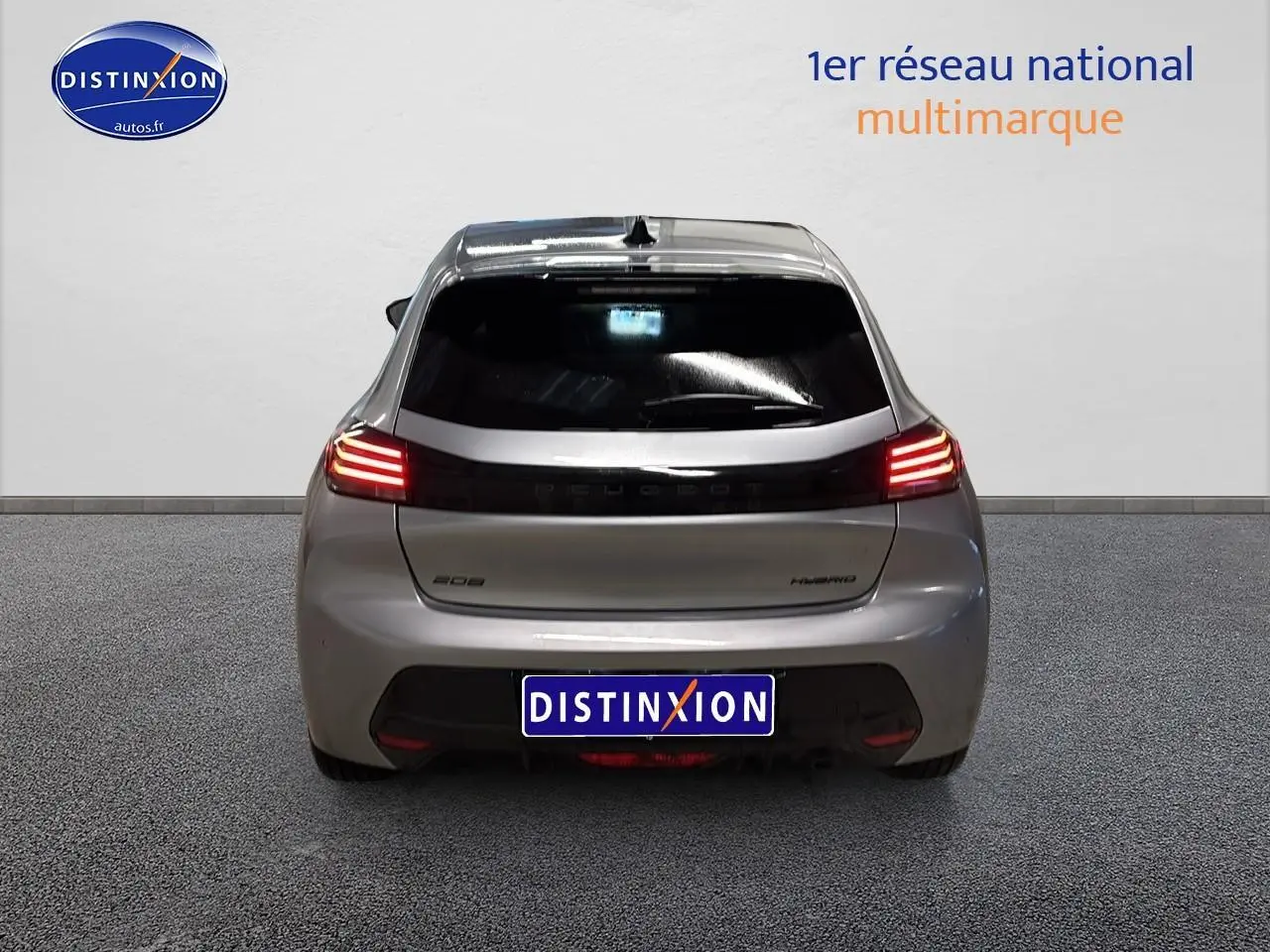 Vue arrière d'une Peugeot 208 1.2 hybrid 110 allure gris artense avec feux arrière LED allumés.