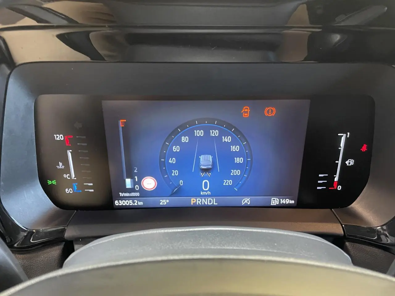 Vue rapprochée du tableau de bord numérique du Ford Tourneo Courier 2024 affichant la vitesse à 0 km/h et les indicateurs de température et carburant.