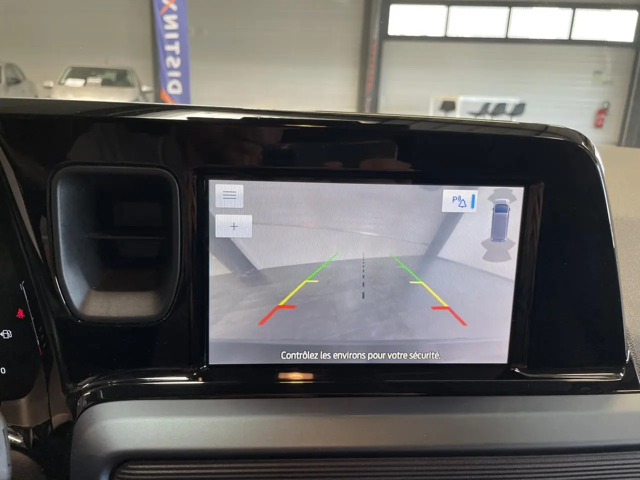 Écran tactile intérieur montrant la caméra de recul du Ford Tourneo Courier gris clair, vue frontale du tableau de bord.