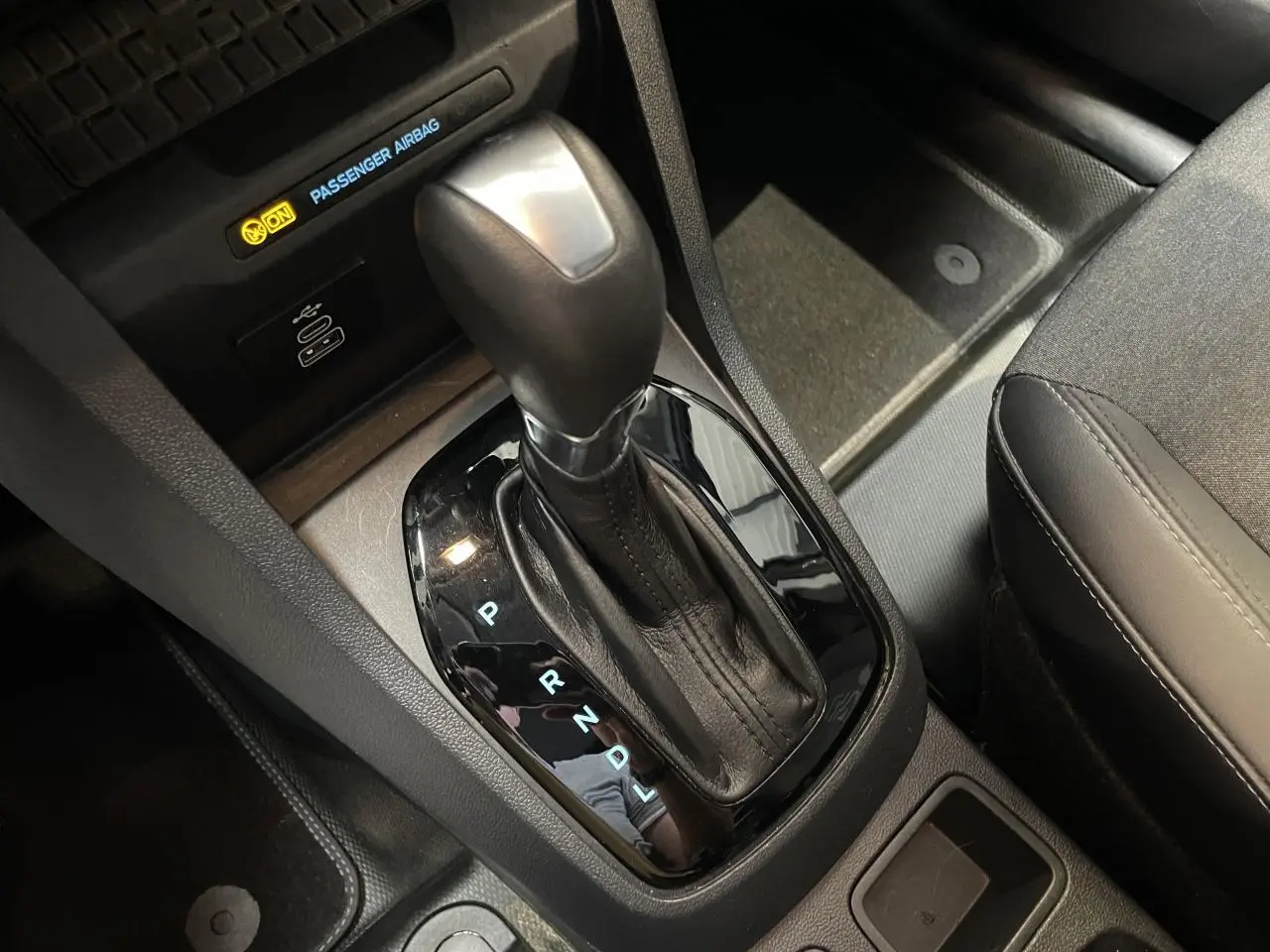 Le levier de vitesses automatique noir du Ford Tourneo Courier 2024, avec port USB-C et siège tissu gris visible.
