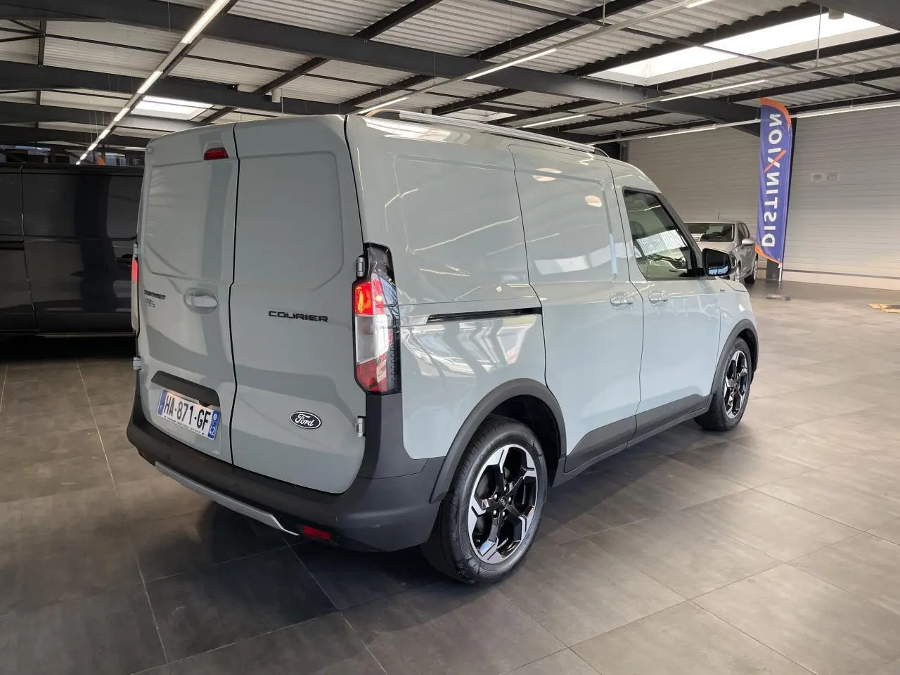 Vue 3/4 arrière droite du Ford Tourneo Courier gris clair avec jantes aluminium noires et pare-chocs noir.