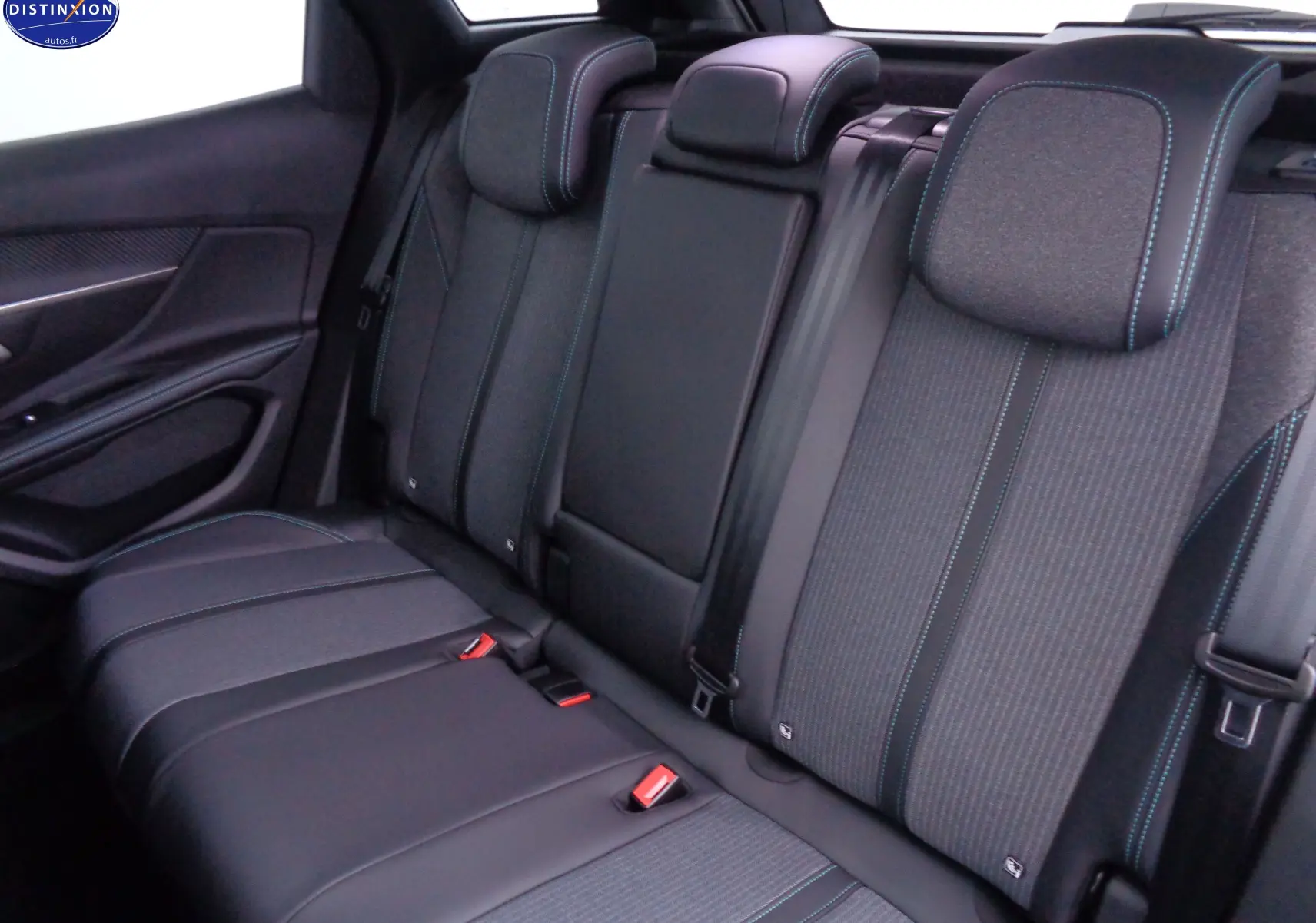 Vue intérieure arrière du Peugeot 3008 2023, sièges noirs en cuir et tissu avec surpiqûres bleues contrastantes.