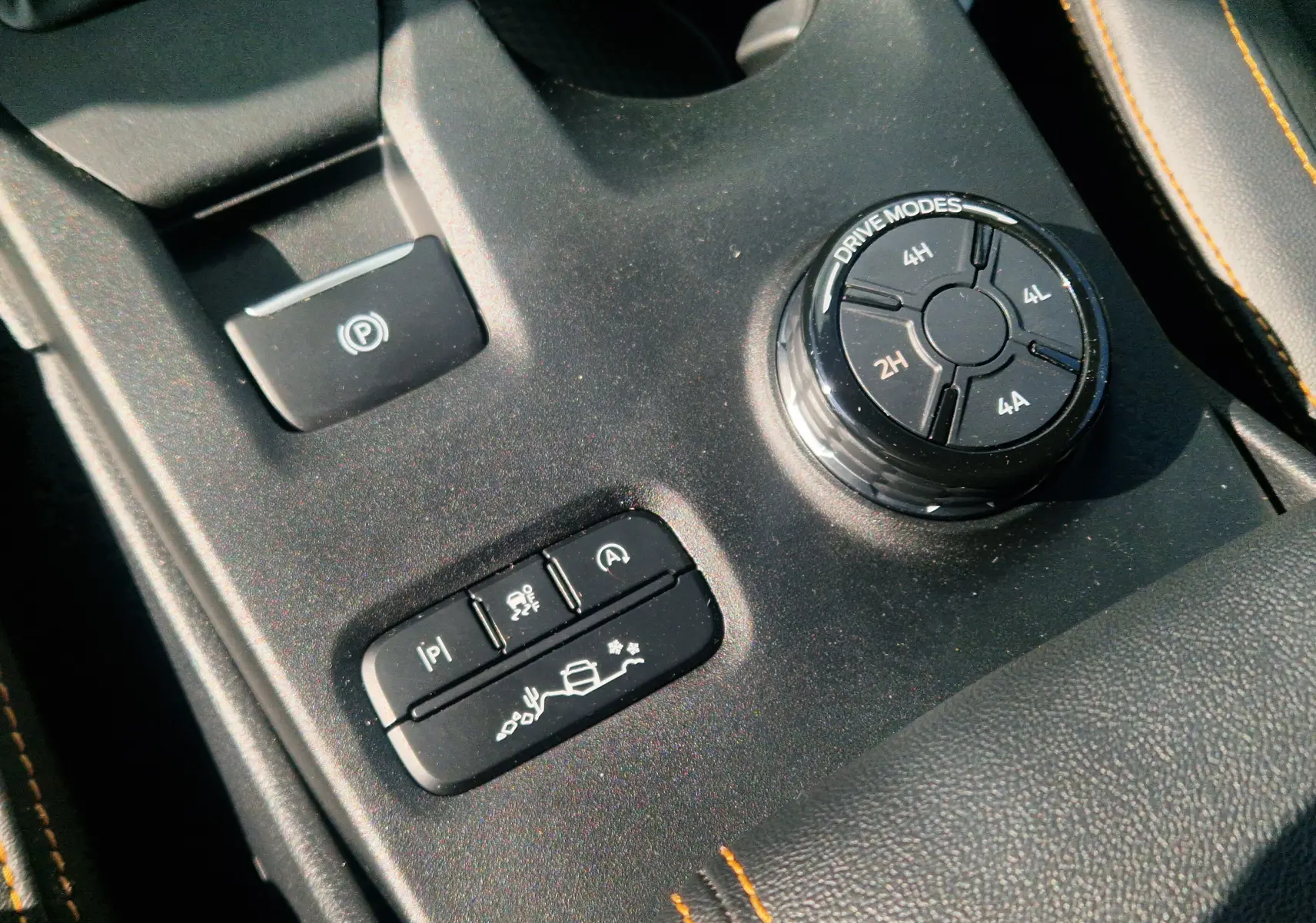 Vue rapprochée de la console centrale ouverte et des sièges en cuir noir avec surpiqûres orange du Ford Ranger Wildtrak 2025.