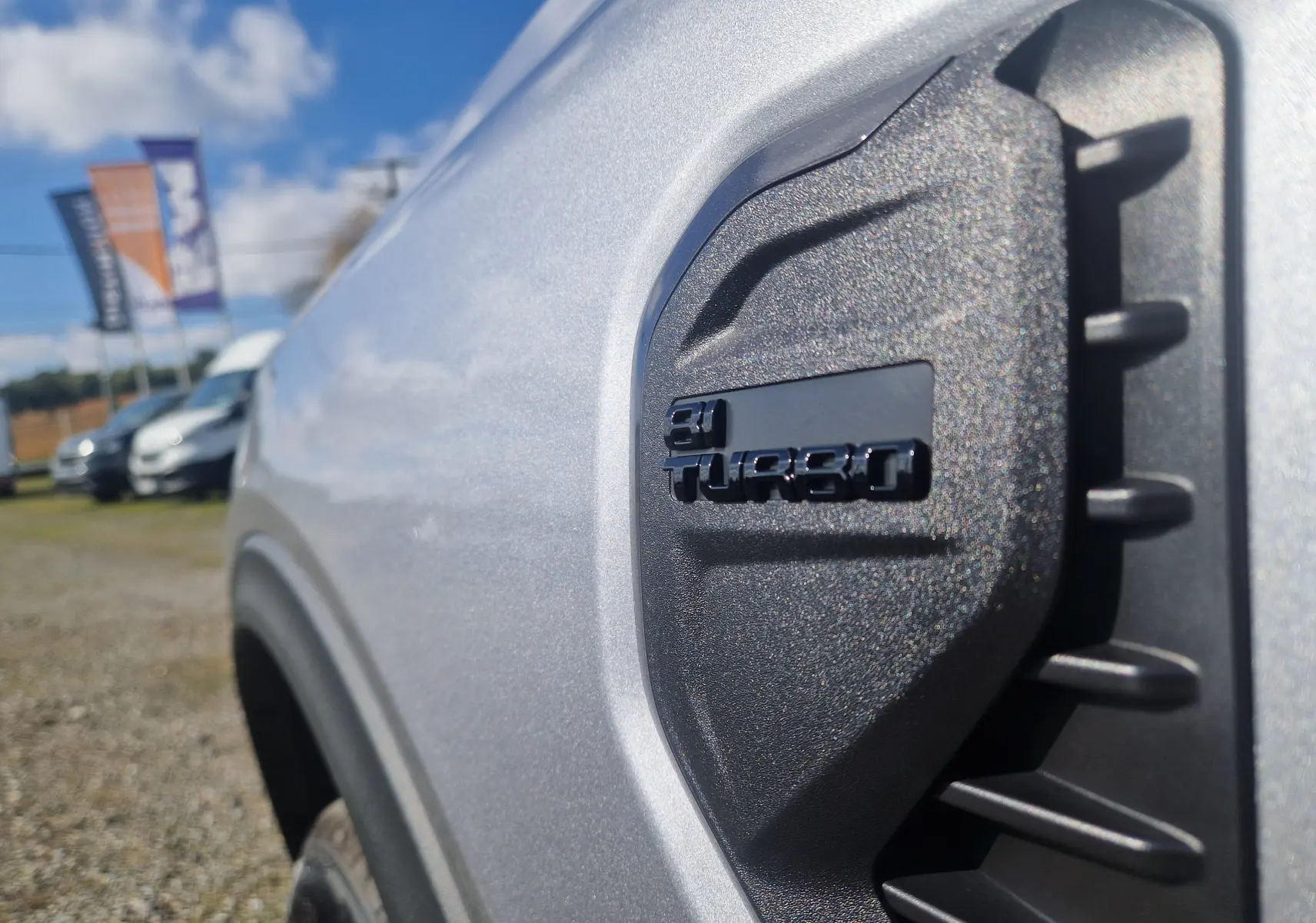 Gros plan sur l'aile avant gauche gris iconic du Ford Ranger Wildtrak avec logo 2.0 Turbo en relief noir.