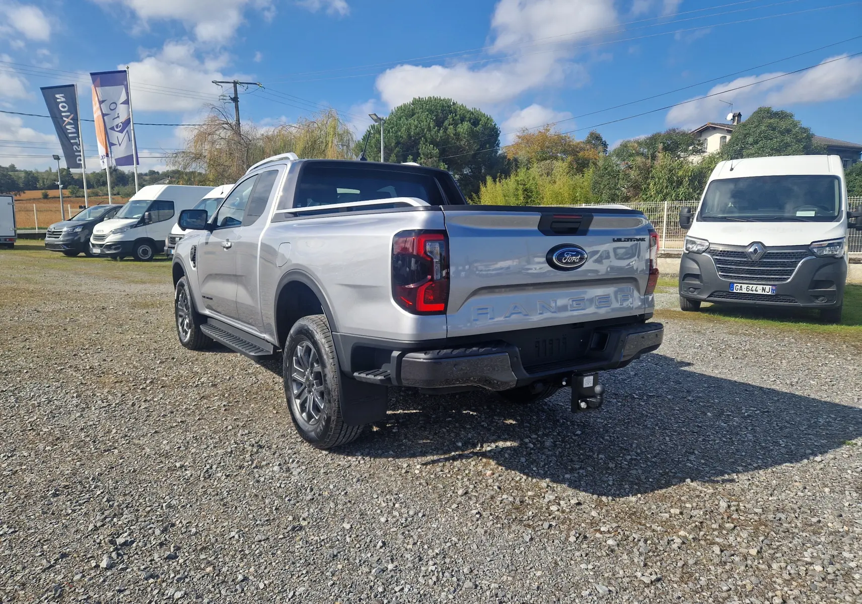 Ford Ranger Super Cabine gris iconic vu en 3/4 arrière droit, avec benne protégée et attelage visible.