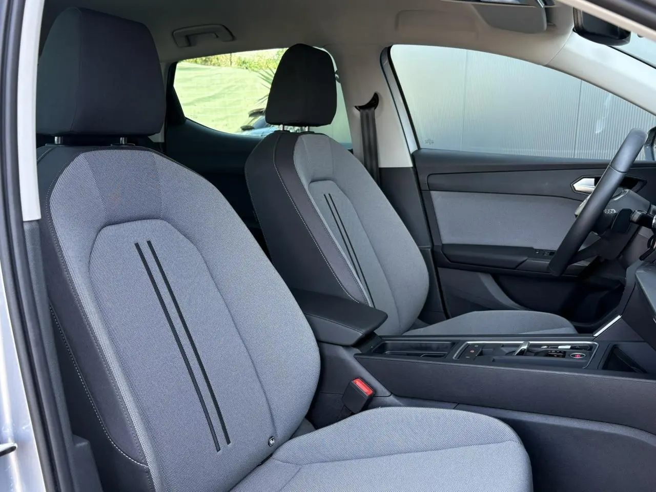 Intérieur avant de la SEAT LEON 2.0 TDI gris argent, vue côté droit sur sièges tissu gris et console centrale noire.