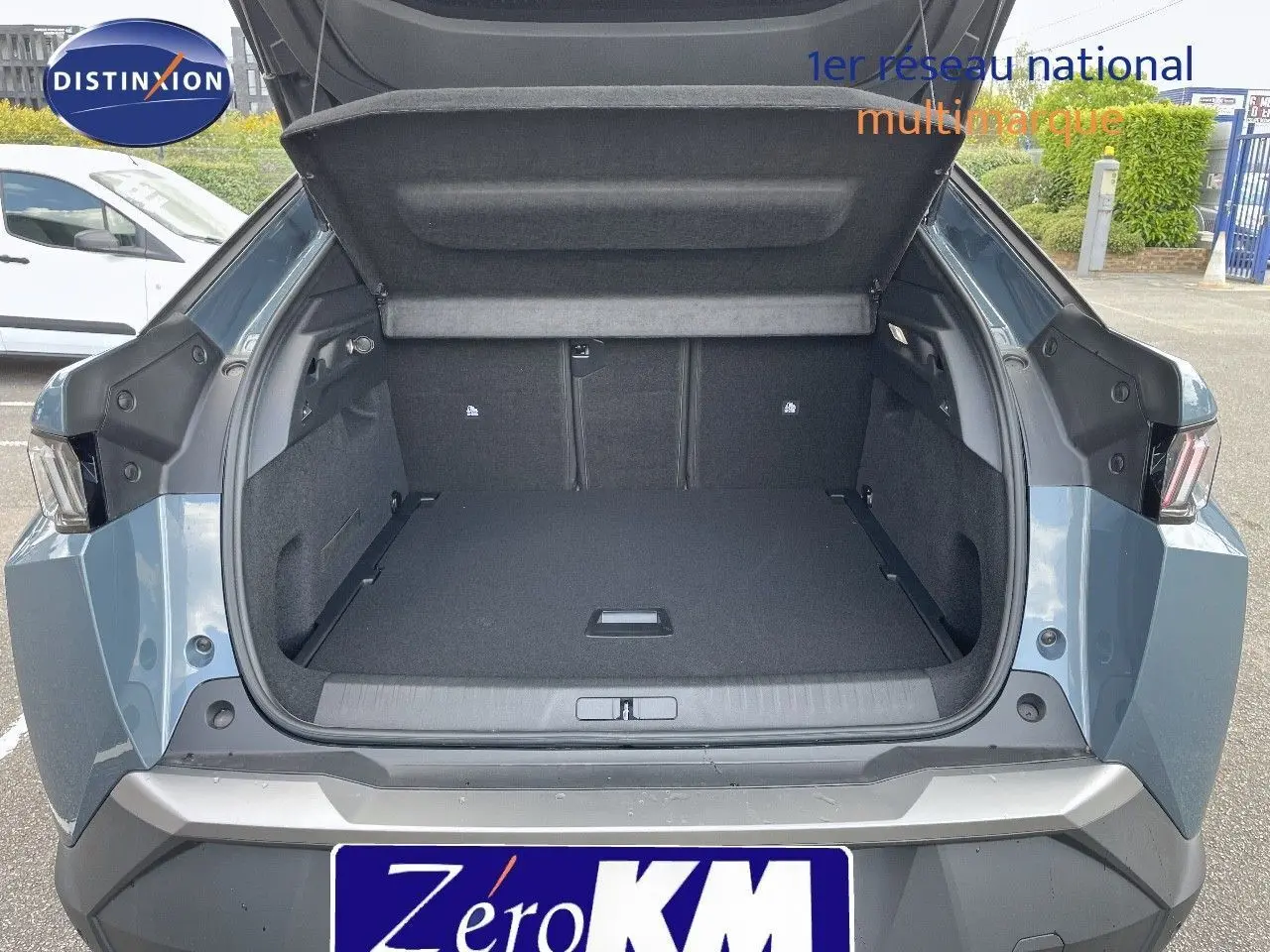 Coffre ouvert vu de l'arrière d'un Peugeot 3008 Hybrid 136ch Allure bleu Ingaro Metal, montrant un espace de chargement spacieux.