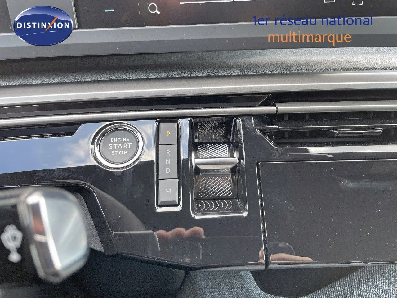 Gros plan sur la console centrale noire brillante du Peugeot 3008 Hybrid 2025 avec bouton start/stop et commandes de boîte automatique.
