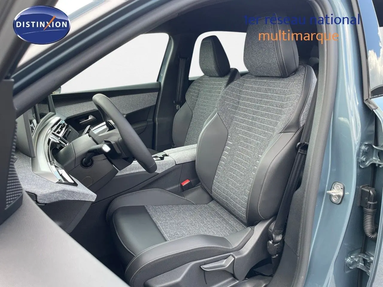 Vue intérieure côté conducteur du Peugeot 3008 Hybrid 2025 en bleu Ingaro Metal, sièges tissu et cuir gris avec surpiqûres.