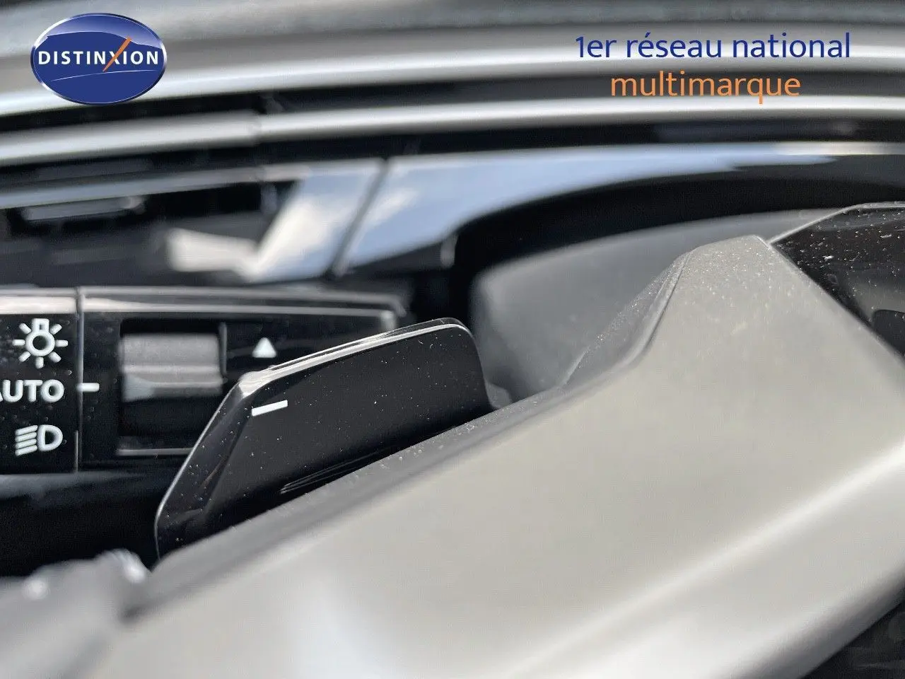 Gros plan sur la commande de feux et la palette de changement de vitesse au volant d'un Peugeot 3008 Hybrid bleu Ingaro Metal.