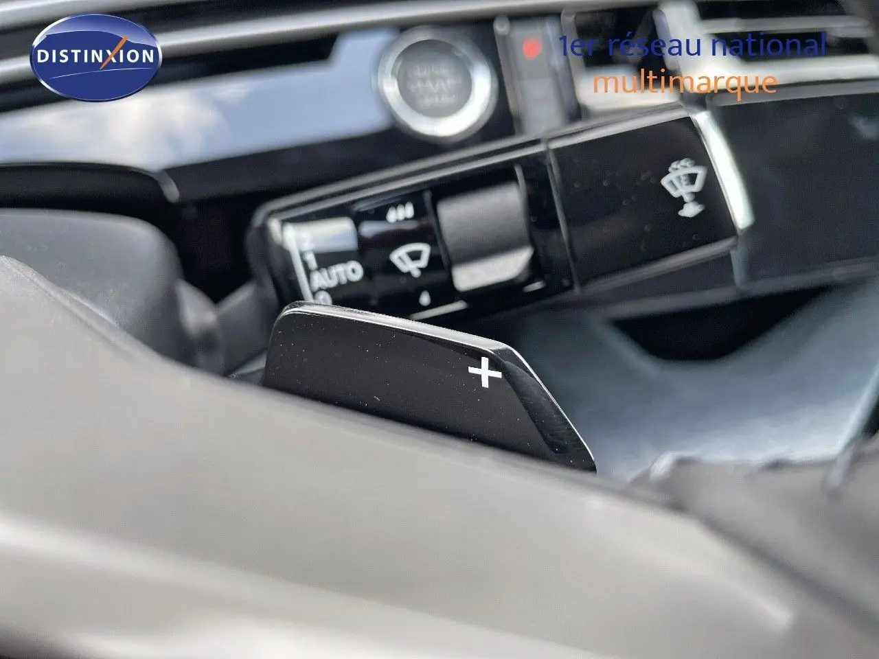 Gros plan sur la palette de changement de vitesse + du Peugeot 3008 Hybrid 2025, intérieur noir avec commandes au volant.