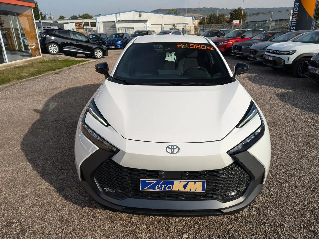 Vue avant d'une Toyota C-HR 2024 blanche avec calandre noire et phares LED anguleux en concession.