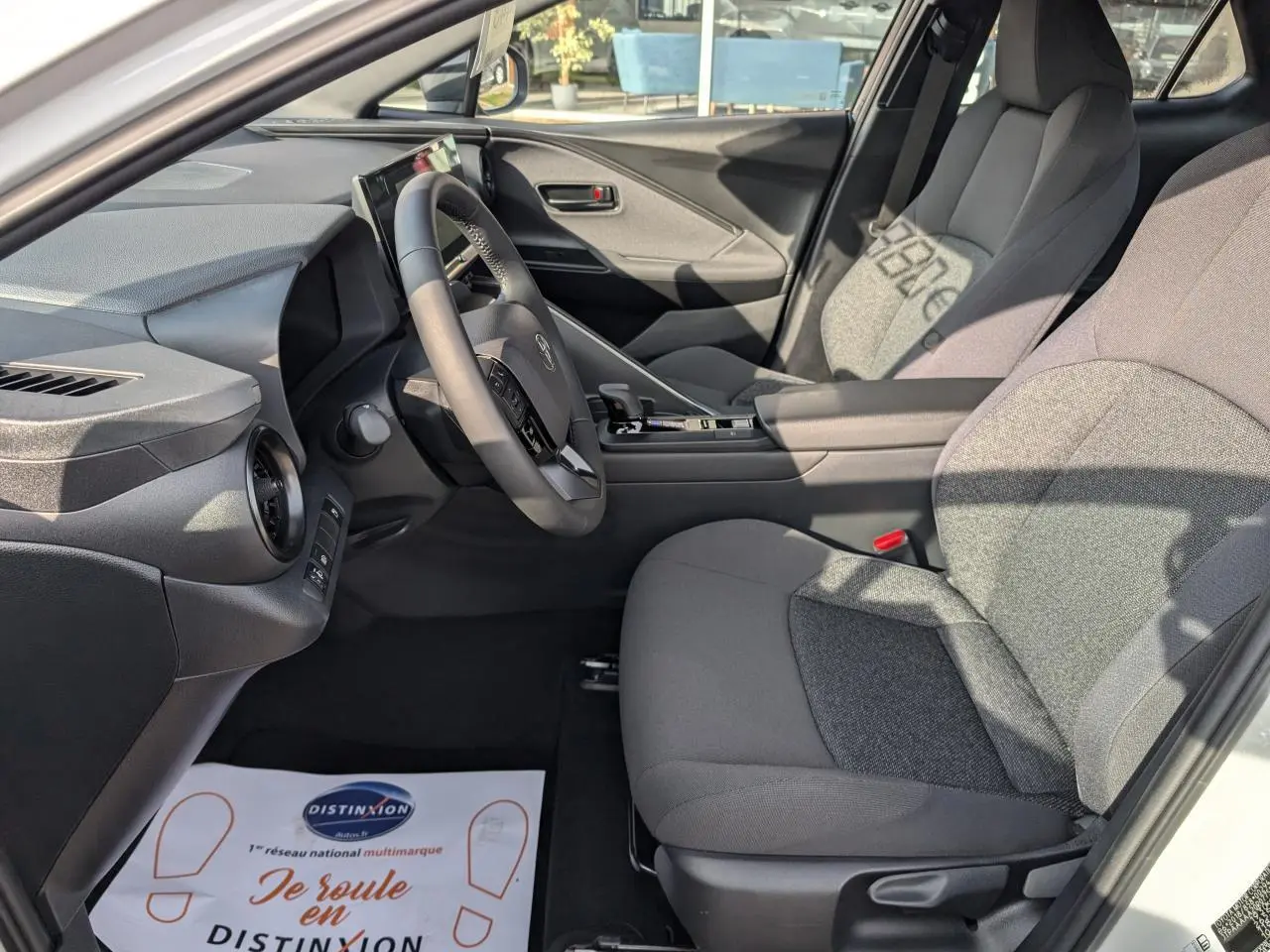 Vue intérieure côté conducteur du Toyota C-HR 1.8 Hybrid 2024, sellerie tissu gris et tableau de bord moderne.