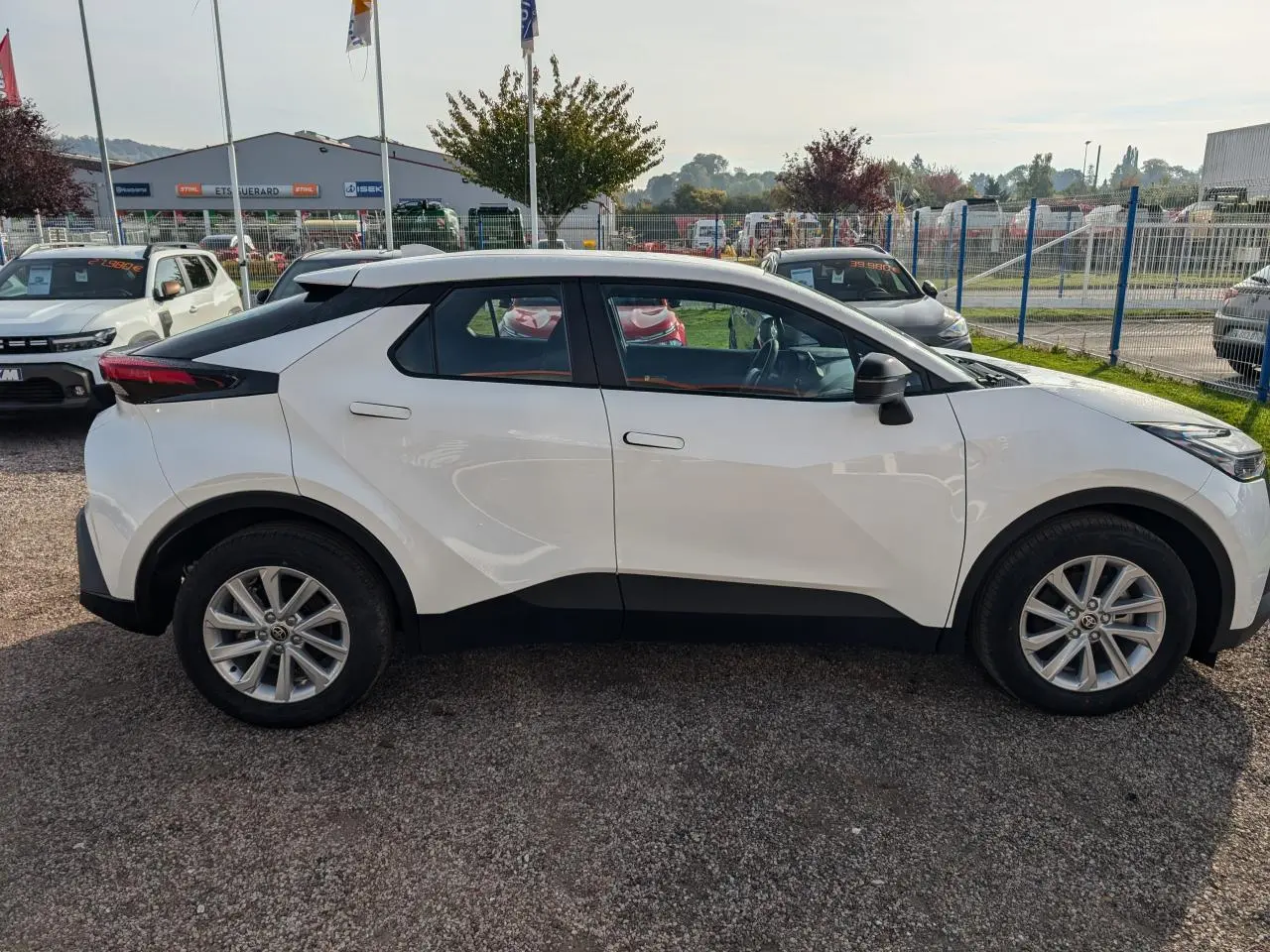 Profil côté gauche du Toyota C-HR 1.8 Hybrid blanc avec jantes alliage 17 pouces et poignées affleurantes.