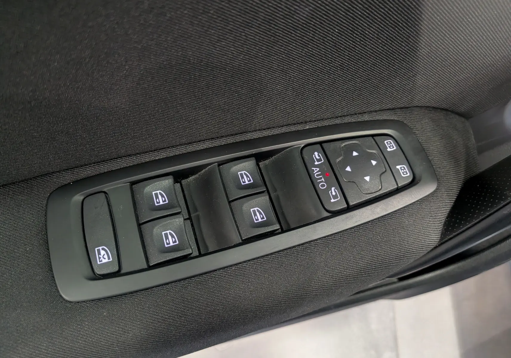 Commande des vitres et rétroviseurs sur la porte côté conducteur d'une Renault Mégane IV Berline gris Titanium, intérieur tissu noir.