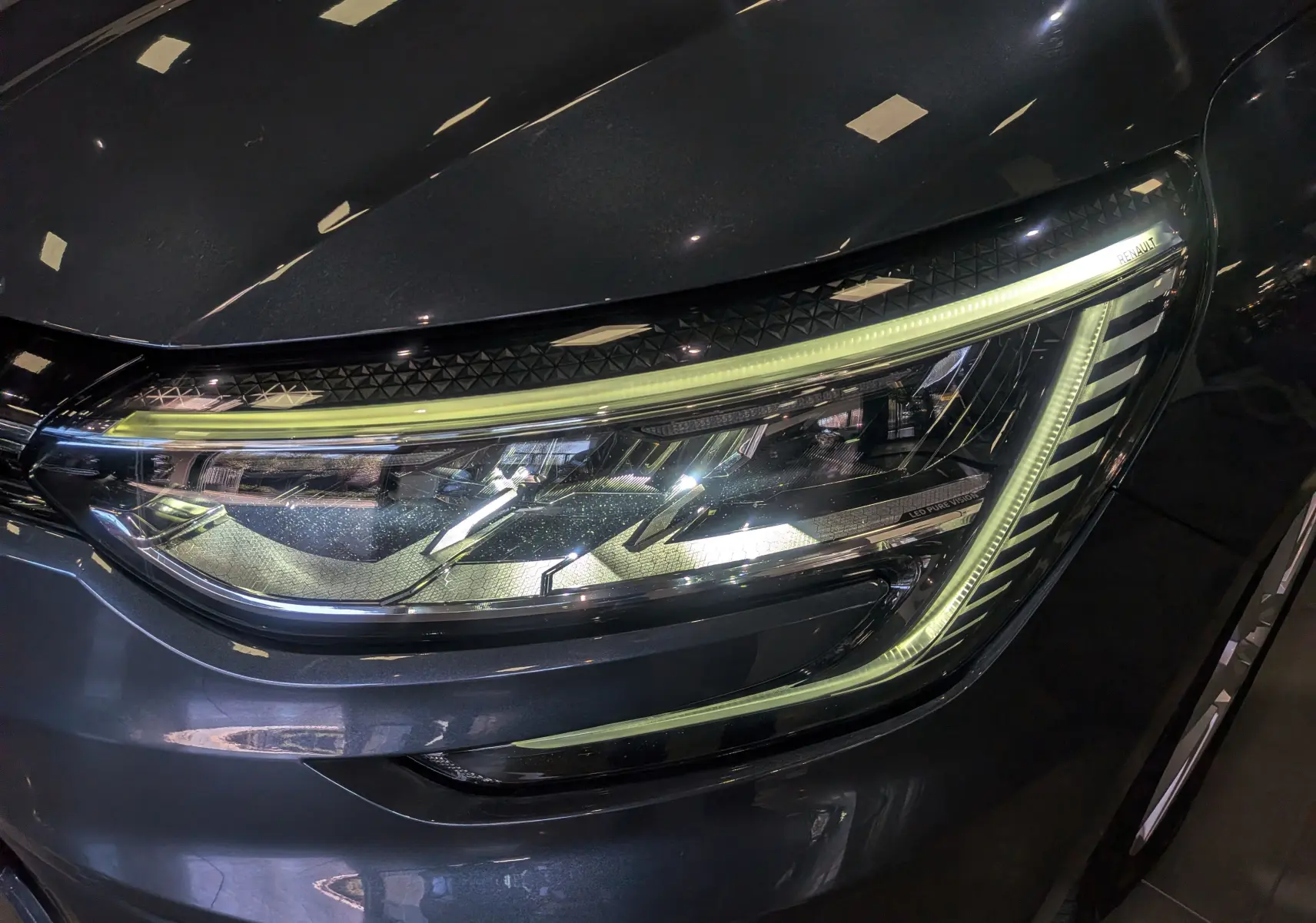 Gros plan sur le phare avant droit LED de la Renault Mégane IV Berline gris Titanium, soulignant ses lignes modernes.