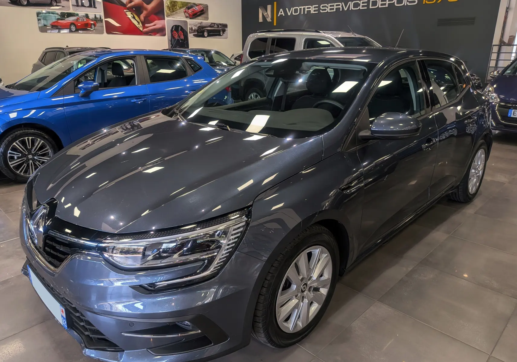Renault Mégane IV Berline Blue dCi 115 Business gris titanium vue 3/4 avant droit en showroom lumineux.