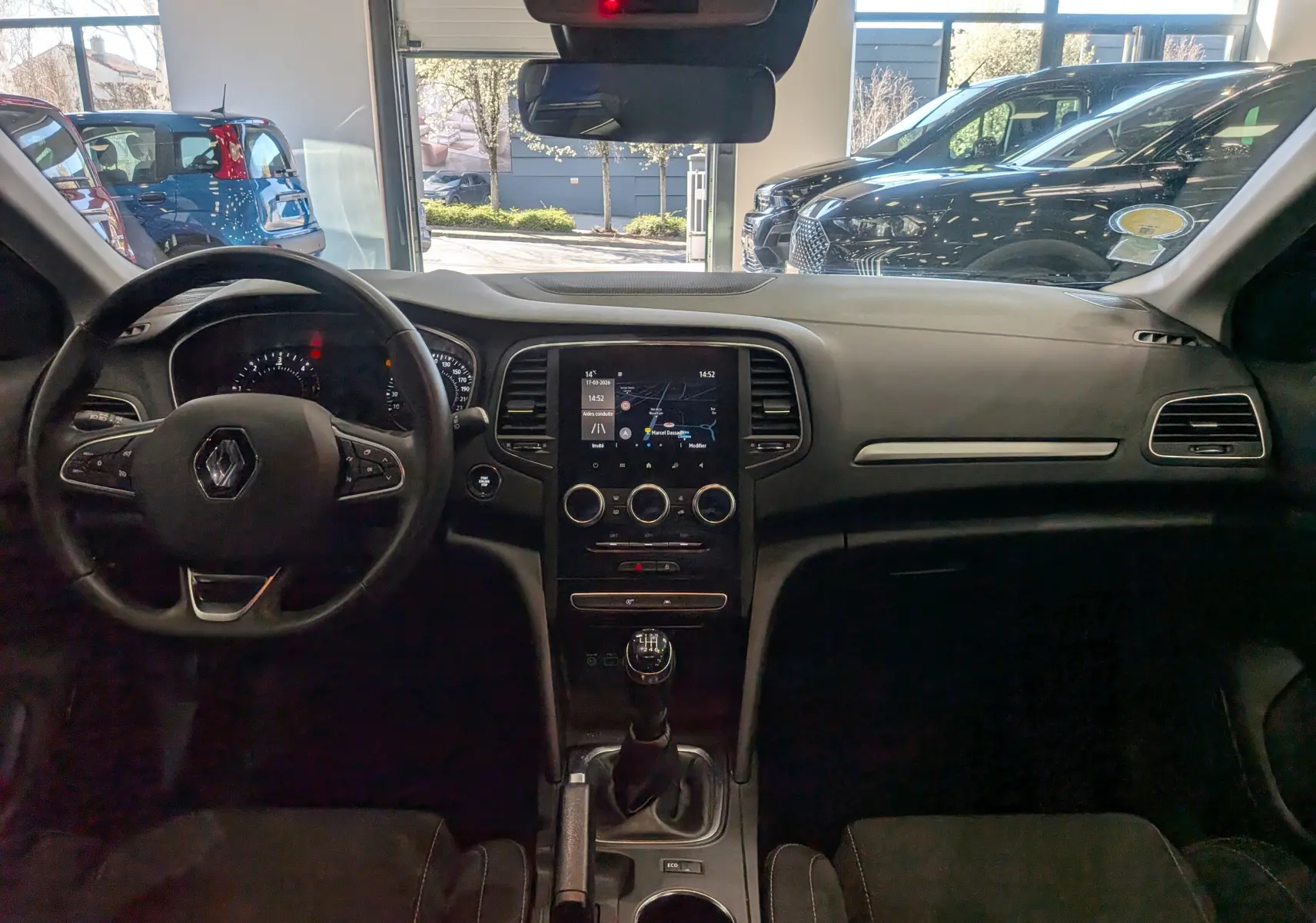 Vue intérieure avant de la Renault Mégane IV Business 2022 gris Titanium, avec tableau de bord et écran tactile central visible.