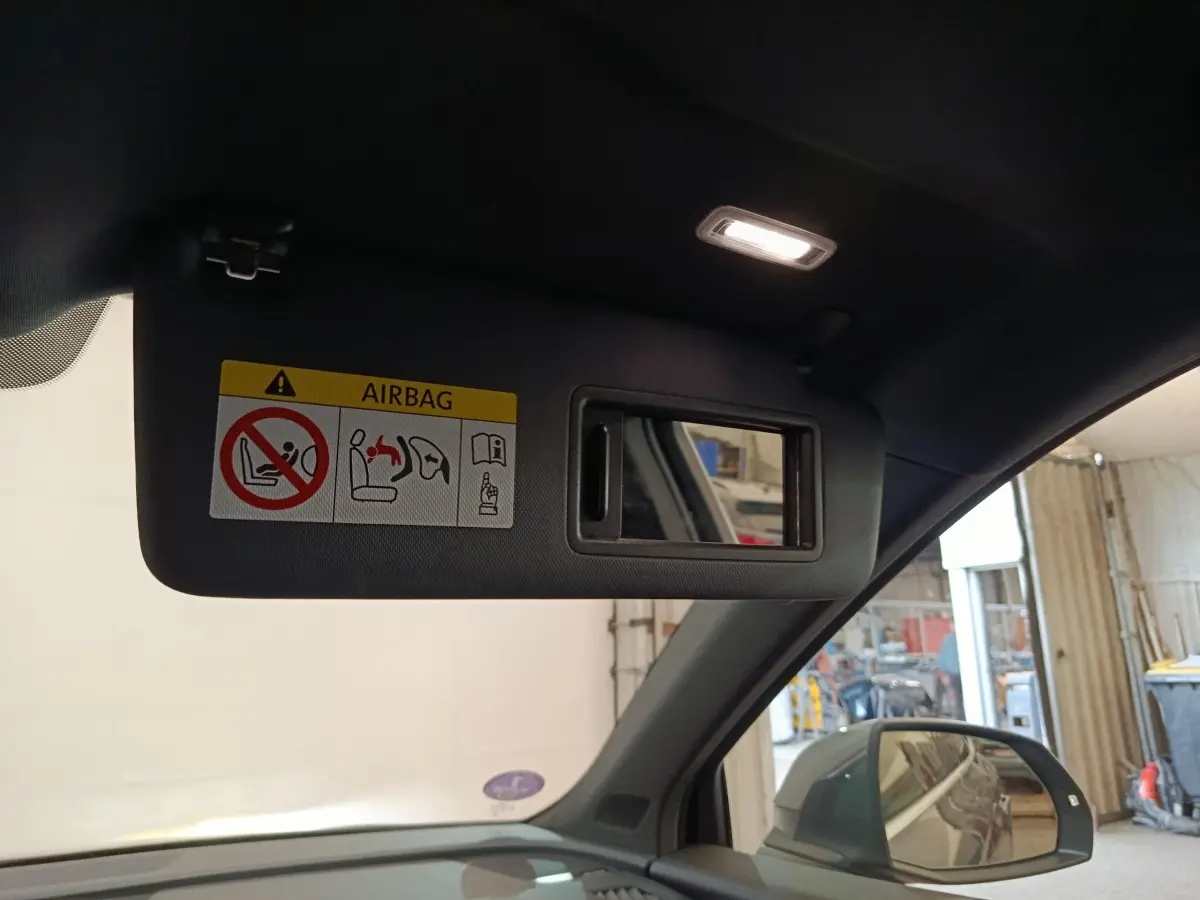 Détail intérieur du pare-soleil côté conducteur avec miroir et étiquette airbag dans un Audi Q5 gris clair 2023 hybride rechargeable.