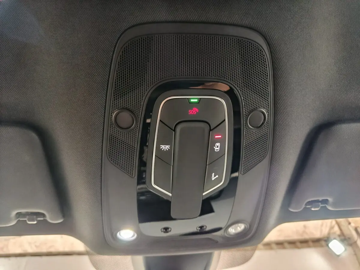 Plafonnier intérieur avec commandes lumineuses et bouton SOS de l'Audi Q5 hybride rechargeable 2023, vue en contre-plongée.