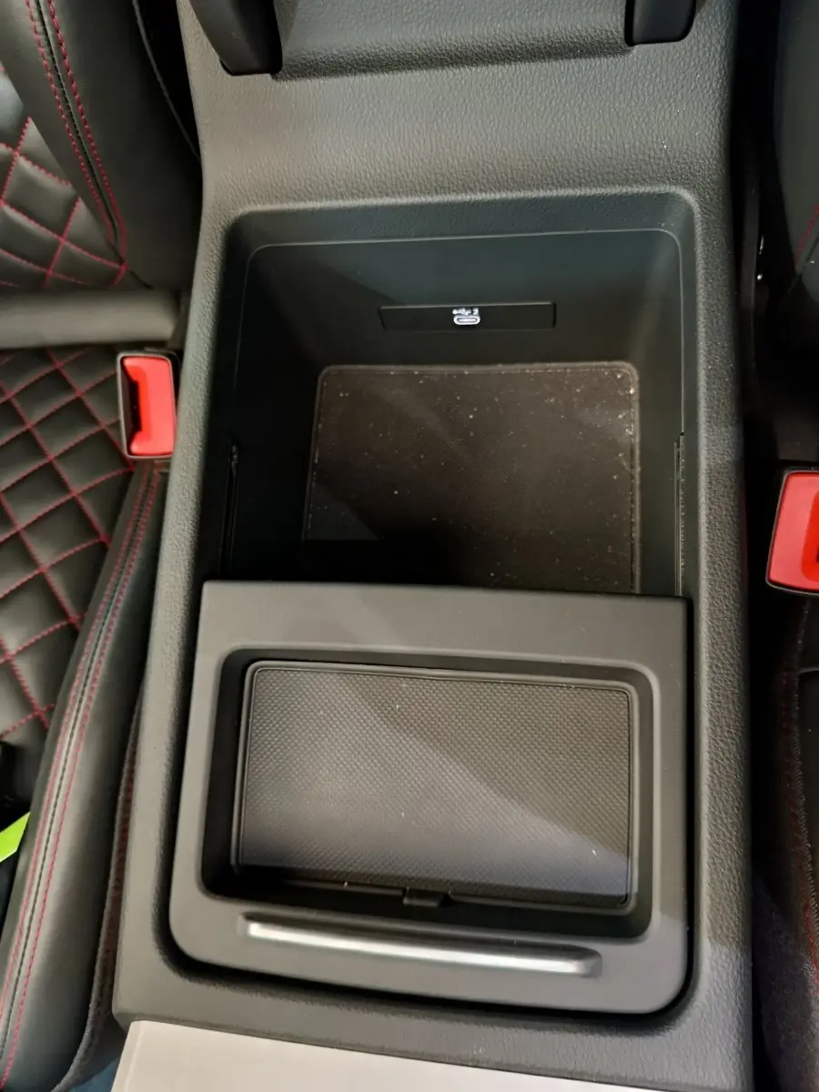Vue plongeante sur la console centrale noire de l'Audi Q5 2023 avec surpiqûres rouges visibles sur les sièges adjacents.