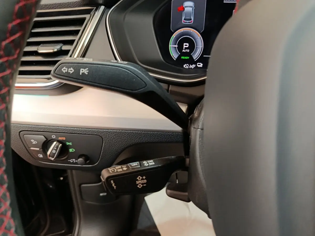 Vue rapprochée du combiné de commandes au volant de l'Audi Q5 2023 gris clair hybride rechargeable, avec affichage numérique.