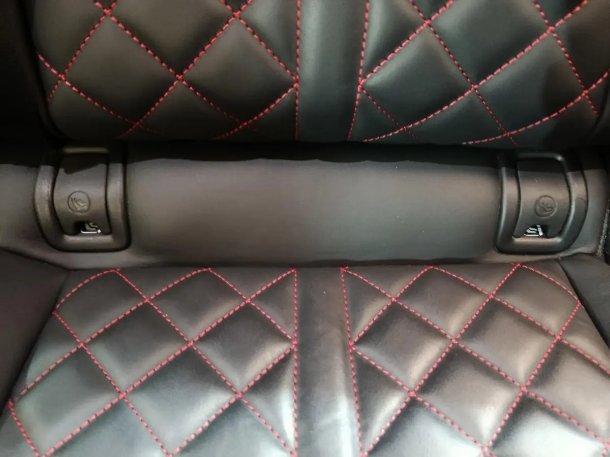 Détail de la sellerie arrière en cuir noir avec surpiqûres rouges du Audi Q5 hybride rechargeable 2023.