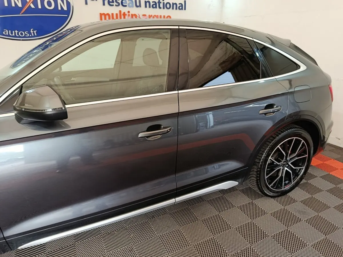 Vue de profil côté gauche d'un Audi Q5 gris clair 2023 avec jantes noires au design sportif.