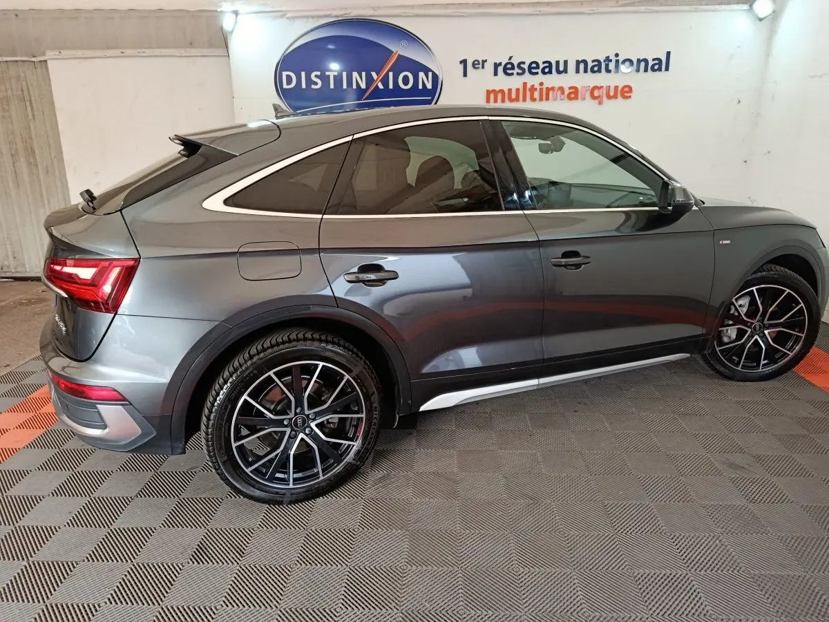 Vue latérale droite d'un Audi Q5 gris clair hybride rechargeable 2023 avec jantes noires et détails chromés.