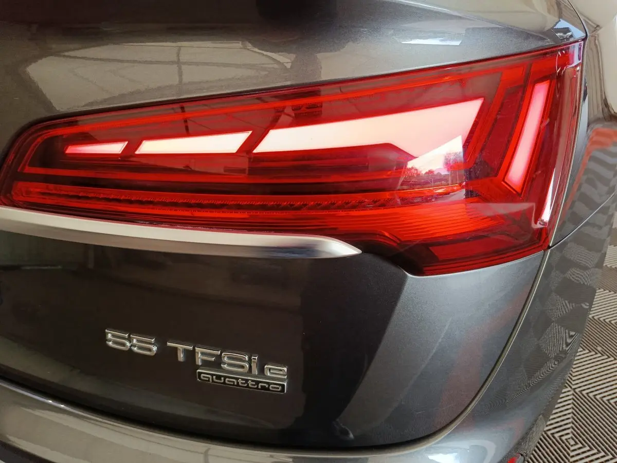 Gros plan sur le feu arrière droit d’un Audi Q5 gris clair 2023 avec badge 55 TFSI e quattro visible.