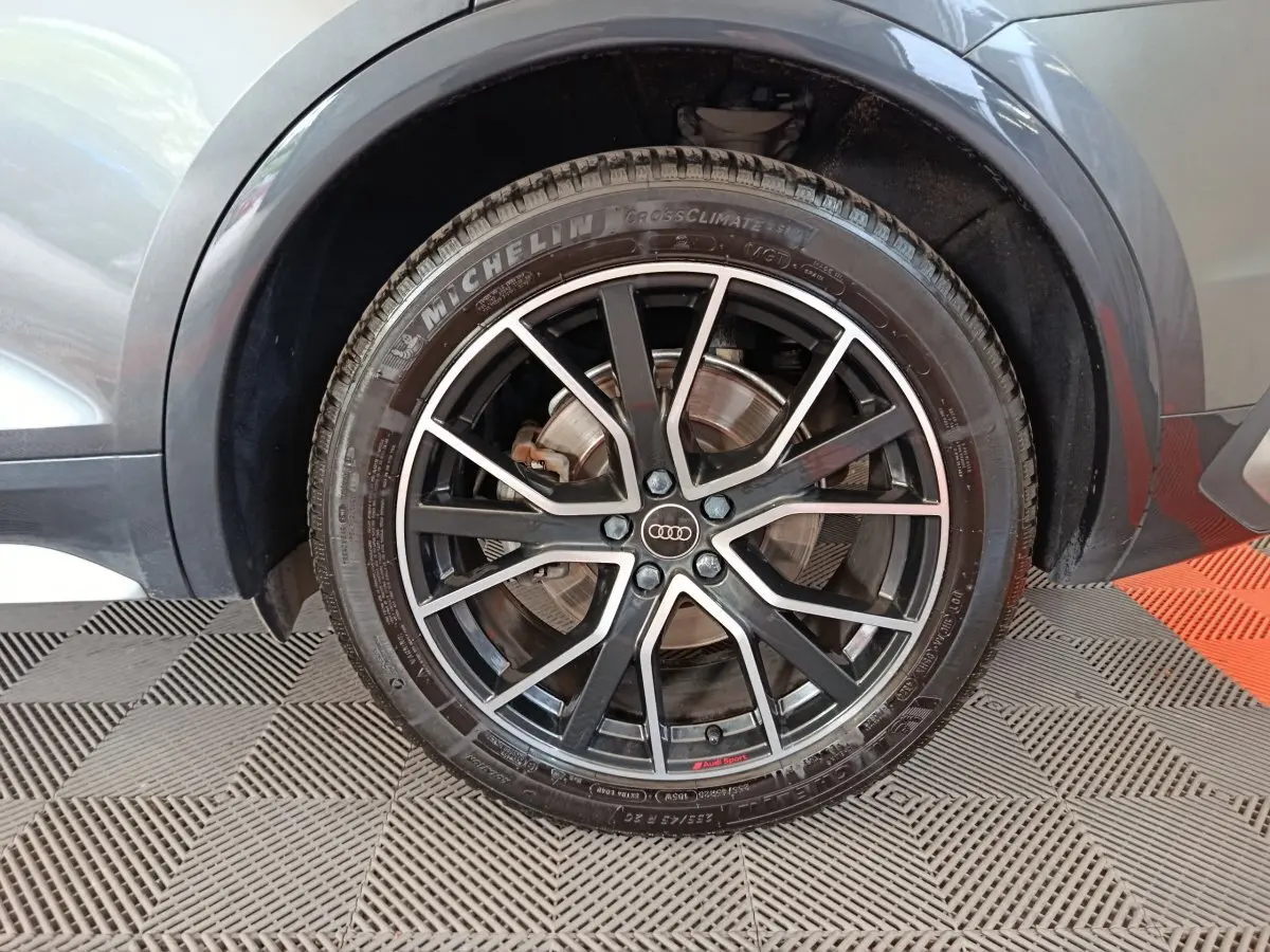 Gros plan sur la roue avant droite gris clair d’un Audi Q5 2023 avec jante noire à branches fines et logo Audi central.