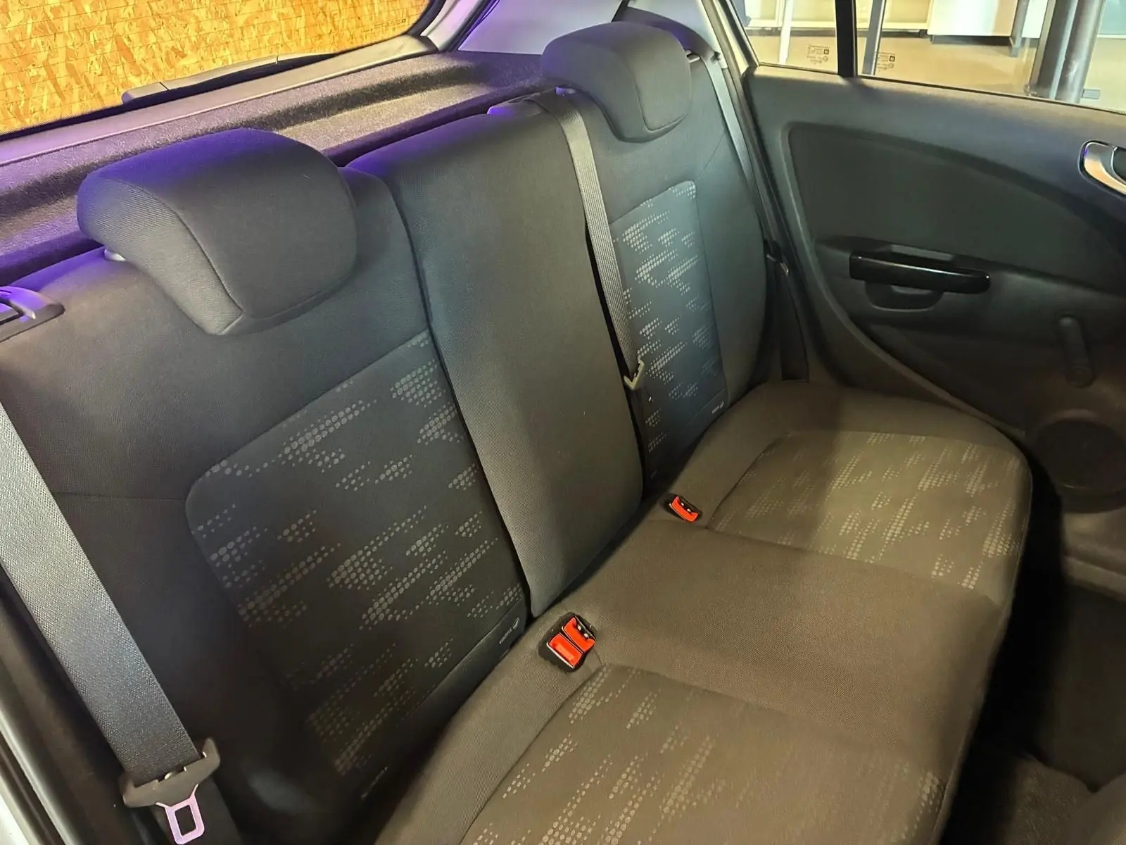 Vue intérieure montrant la banquette arrière en tissu noir de l'Opel Corsa gris clair, côté droit avec ceinture de sécurité.