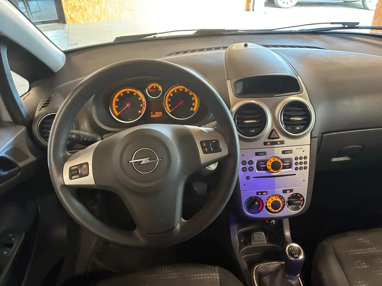 Intérieur noir de l’Opel Corsa 2012, vue du poste de conduite avec volant, tableau de bord et console centrale éclairés.
