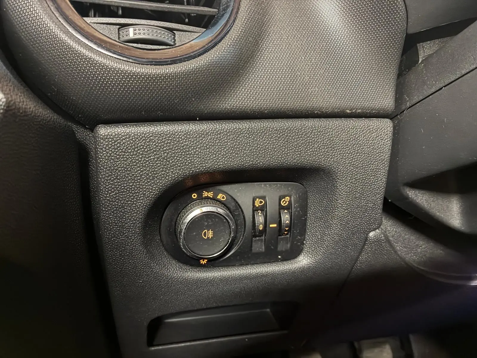 Gros plan sur le panneau de commande des phares et éclairages intérieurs d’une Opel Corsa gris clair, intérieur noir.