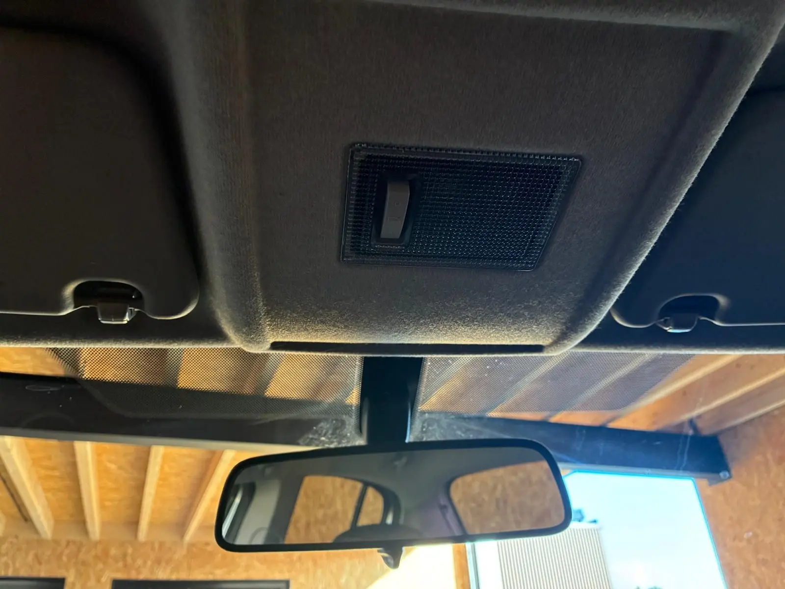 Vue intérieure centrée sur le rétroviseur et le plafonnier d'une Opel Corsa gris clair de 2012.