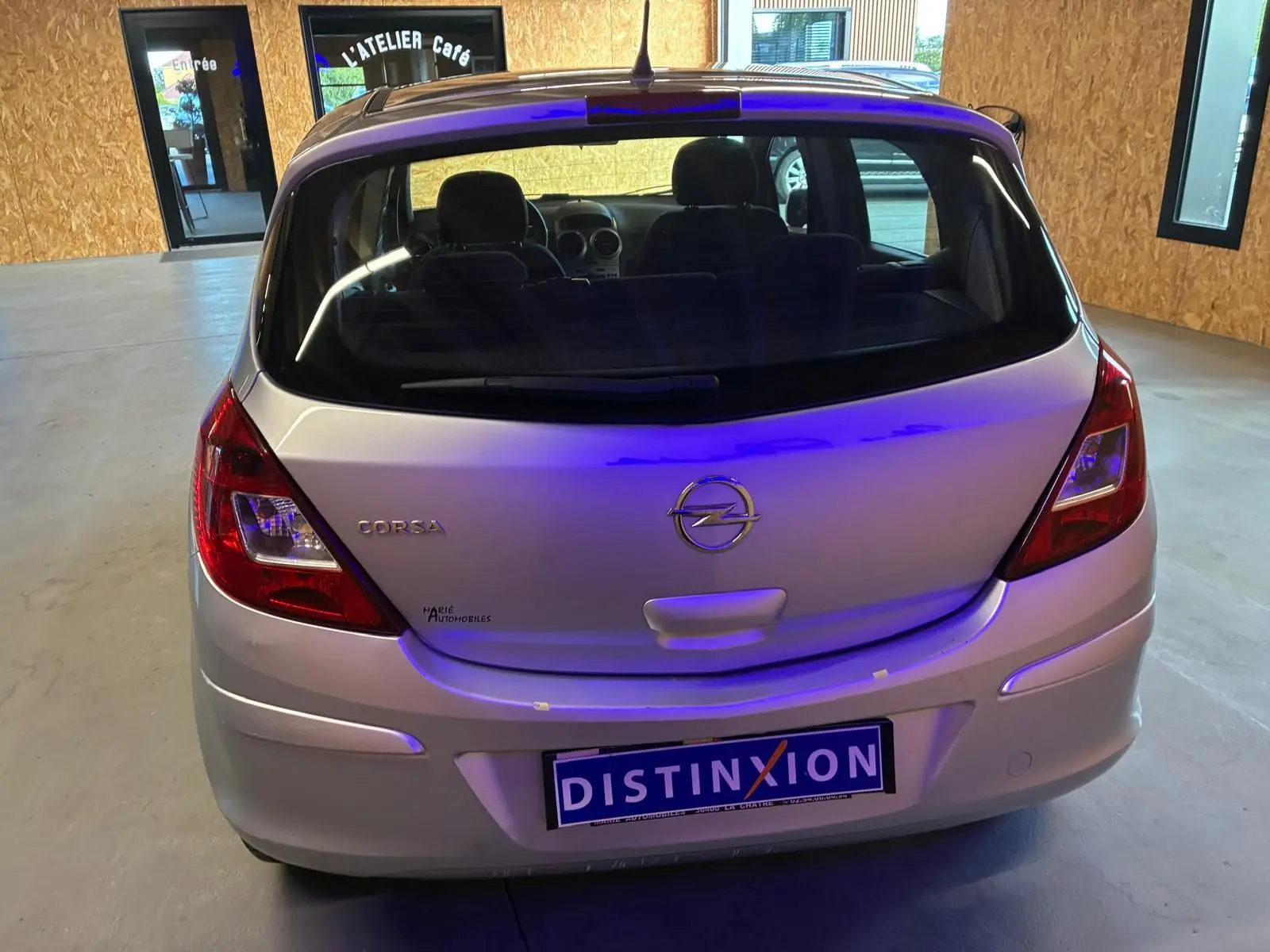 Vue arrière d'une Opel Corsa gris clair de 2012, avec cinq portes et logo distinctif sur le hayon.