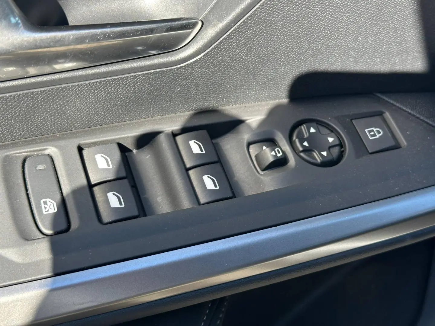 Gros plan sur les commandes de vitres et rétroviseurs côté conducteur du Peugeot 5008 Hybrid blanc Okénite.