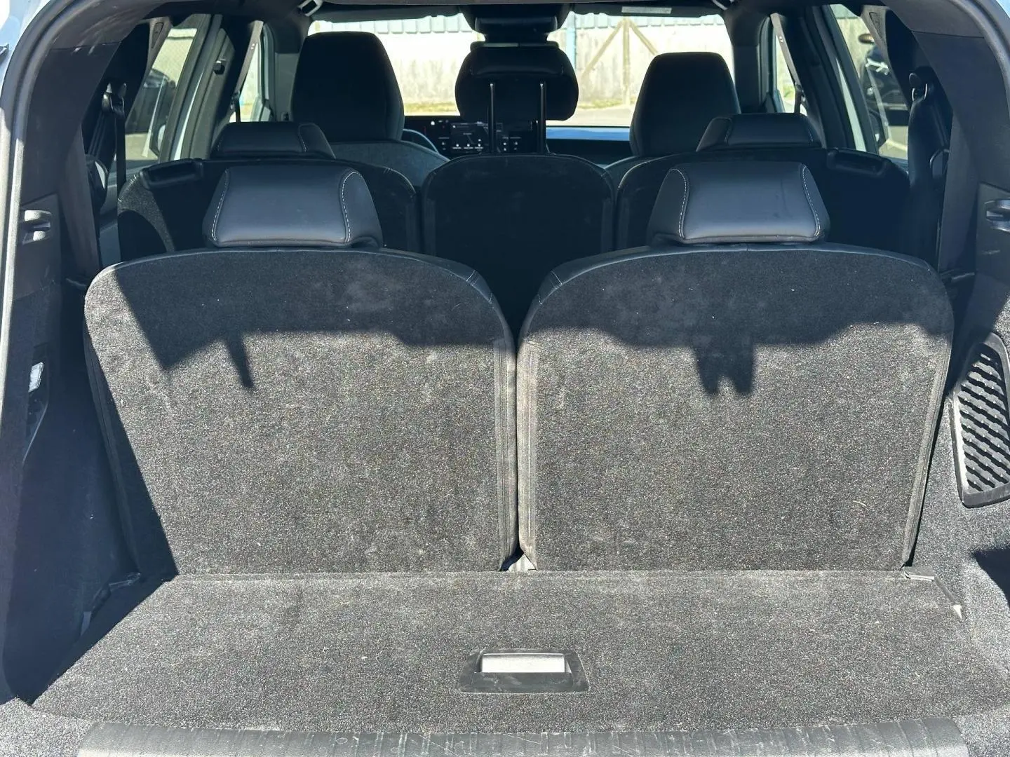 Vue arrière du coffre du Peugeot 5008 Hybrid blanc avec les sièges rang 3 relevés en tissu noir.