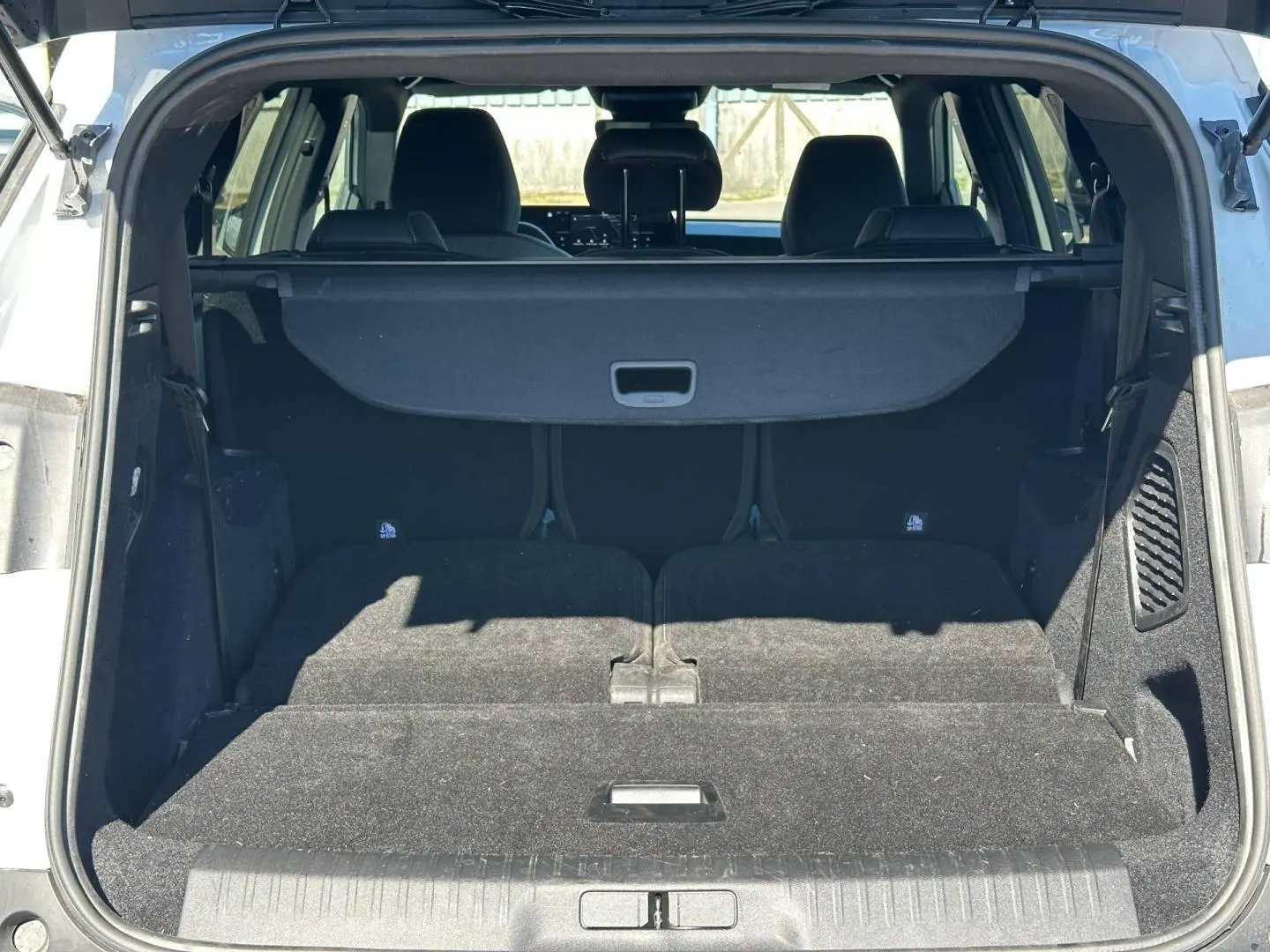 Coffre ouvert du Peugeot 5008 blanc Okénite, vue arrière montrant les sièges arrière rabattus et la plage arrière.