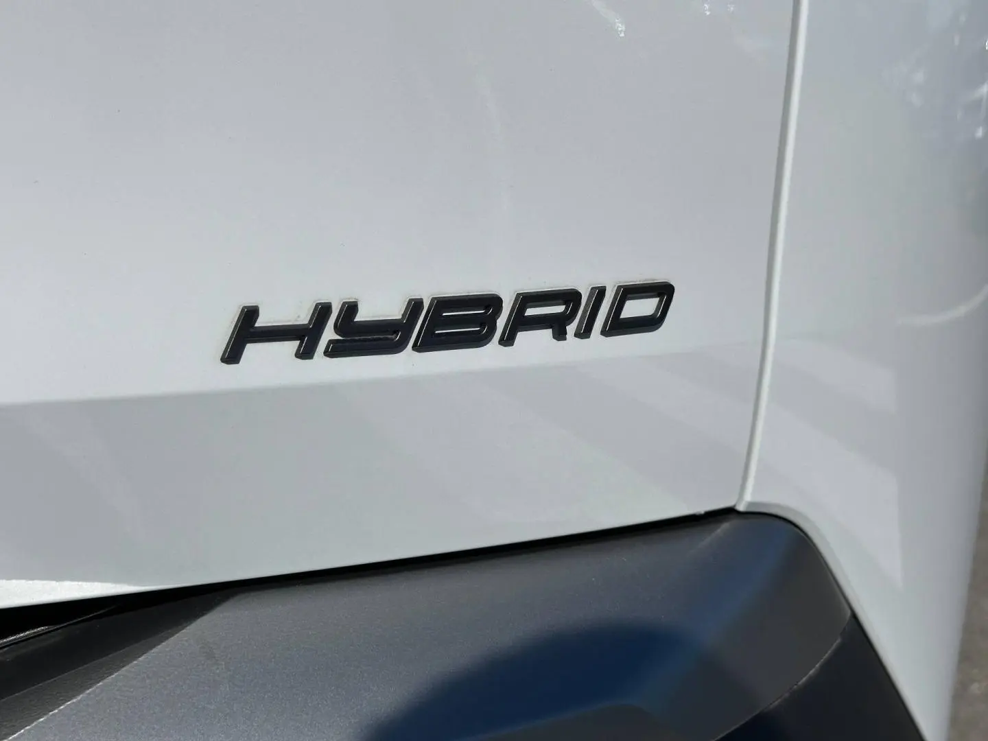 Gros plan sur l’inscription Hybrid en noir sur la carrosserie blanche Okénite d’un Peugeot 5008 2025.