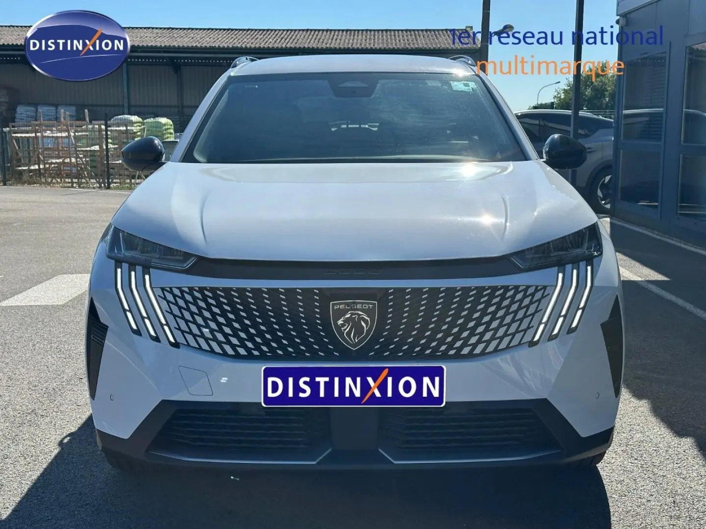 Vue avant d'un Peugeot 5008 Hybrid blanc Okénite avec calandre distinctive et feux LED en griffes.