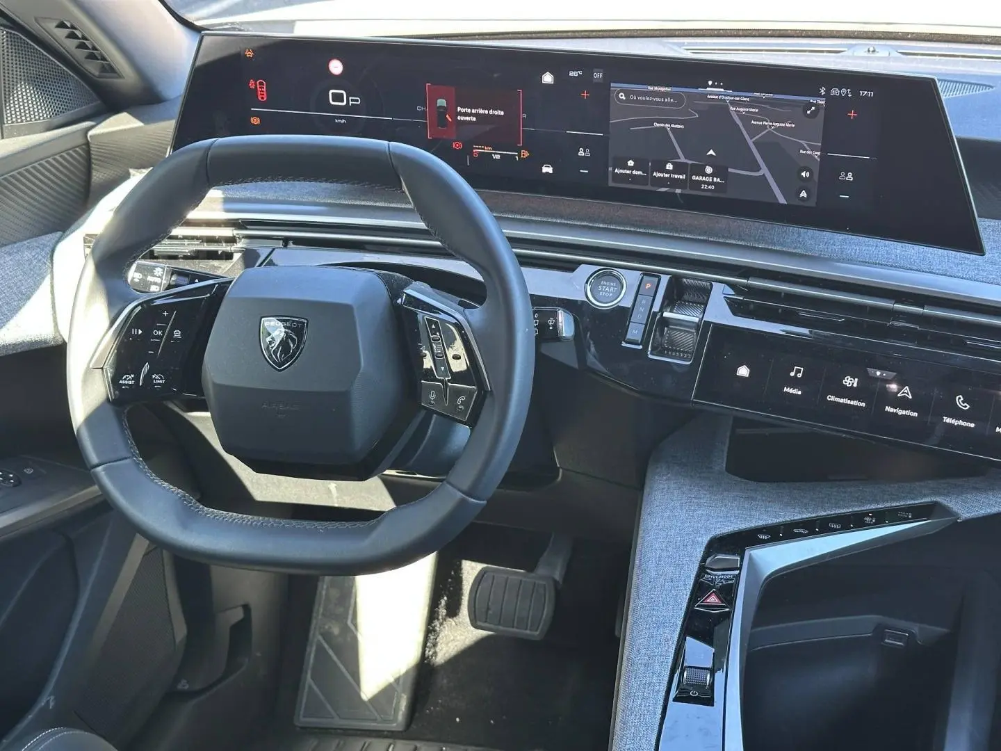 Vue intérieure du tableau de bord et volant cuir multifonction du Peugeot 5008 Hybrid 2025 avec écran tactile panoramique.