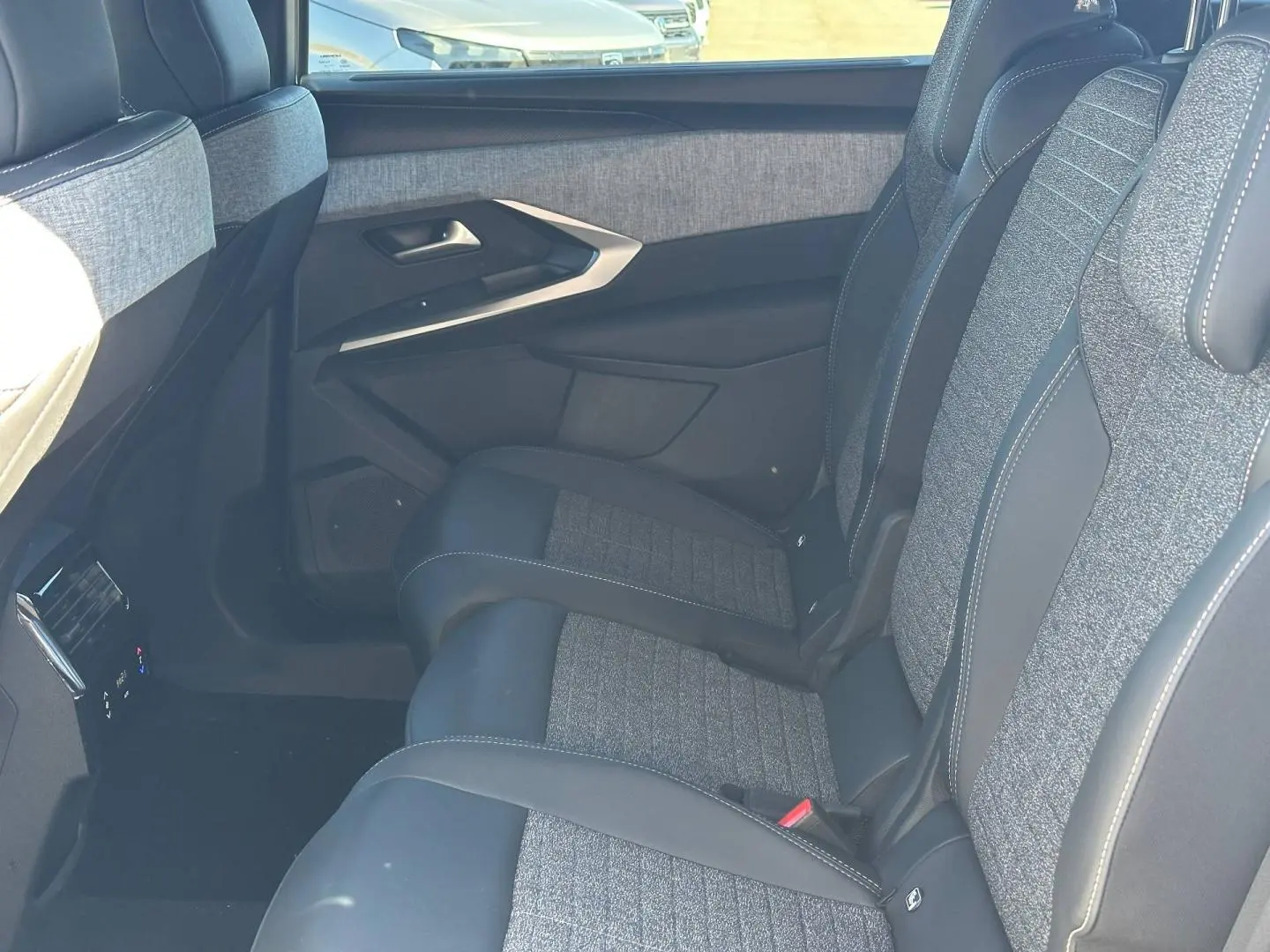 Vue côté droit des sièges arrière gris tissu et cuir du Peugeot 5008 Hybrid 2025 avec accoudoir central rabattable.