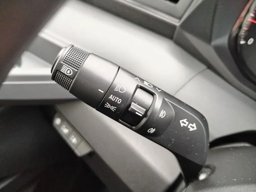 Gros plan sur la commande des phares et clignotants noire à l'intérieur du Nissan Interstar Fourgon blanc.
