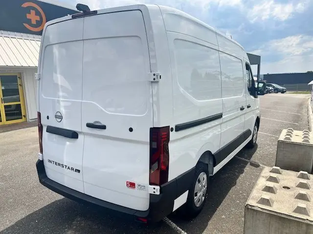Vue 3/4 arrière droite d'un fourgon Nissan Interstar blanc 2025 avec portes arrière pleines et feux rouges verticaux.