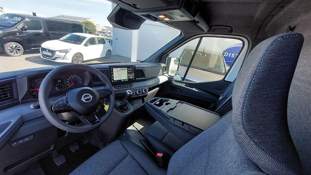 Vue intérieure côté conducteur du Nissan Interstar Fourgon blanc 2025, tableau de bord moderne avec écran tactile et volant multifonction.