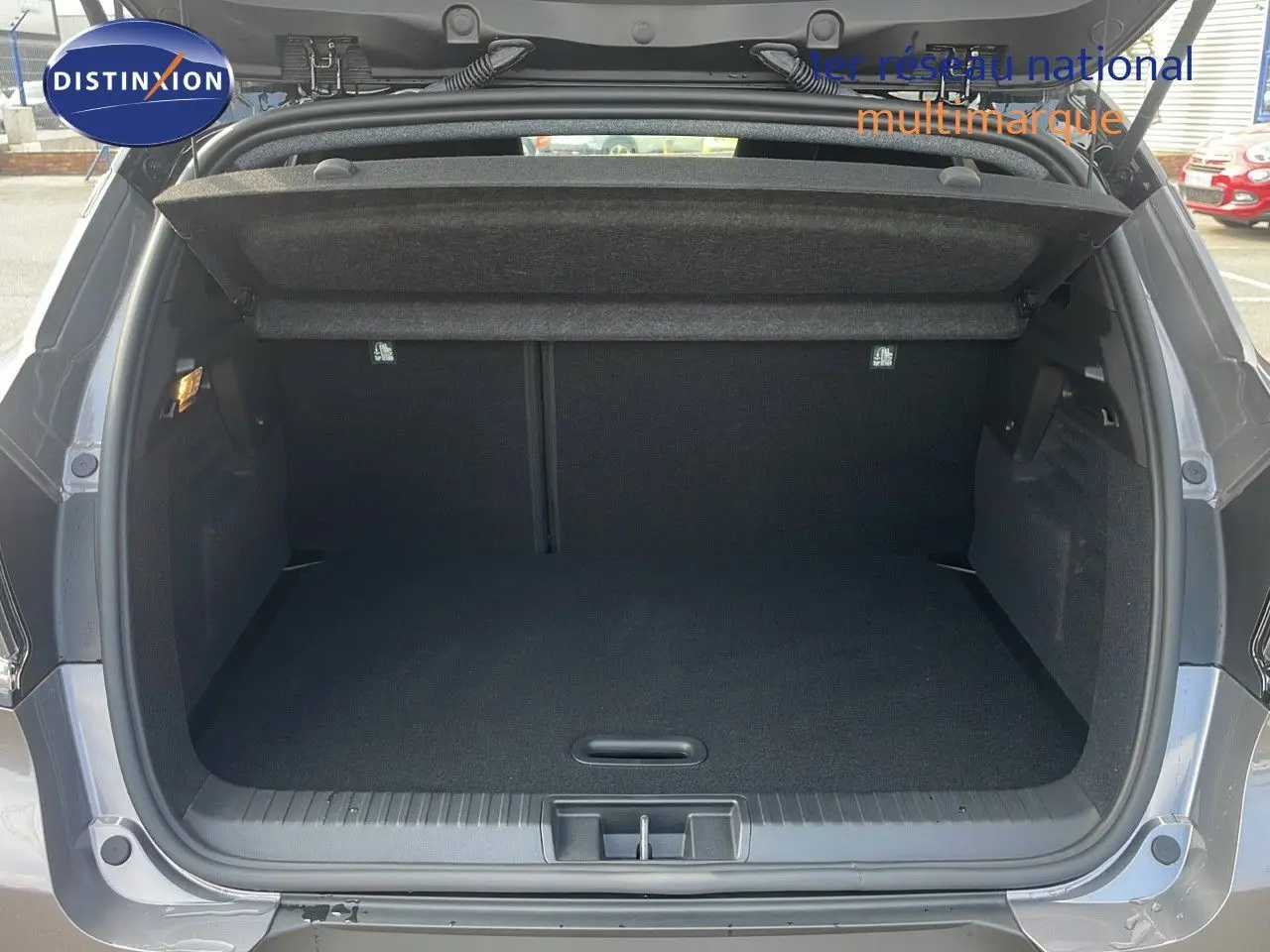 Coffre ouvert d'un Renault Captur E-Tech hybride gris Cassiopée métal avec toit noir, montrant un espace de chargement vide.